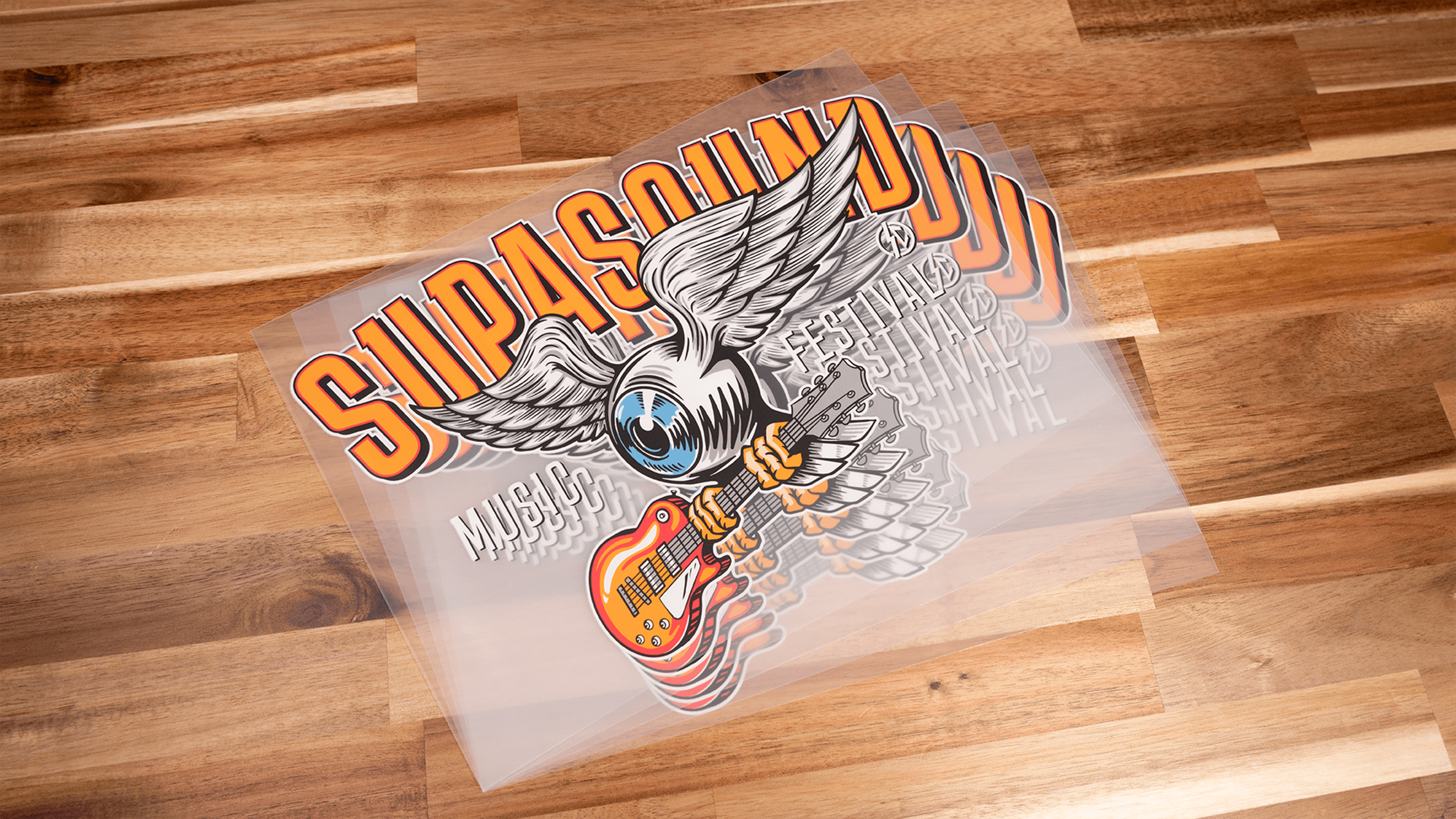 Festival merchandise t-shirt design with winged eagle, guitar, and Supasonik branding on wooden floor
