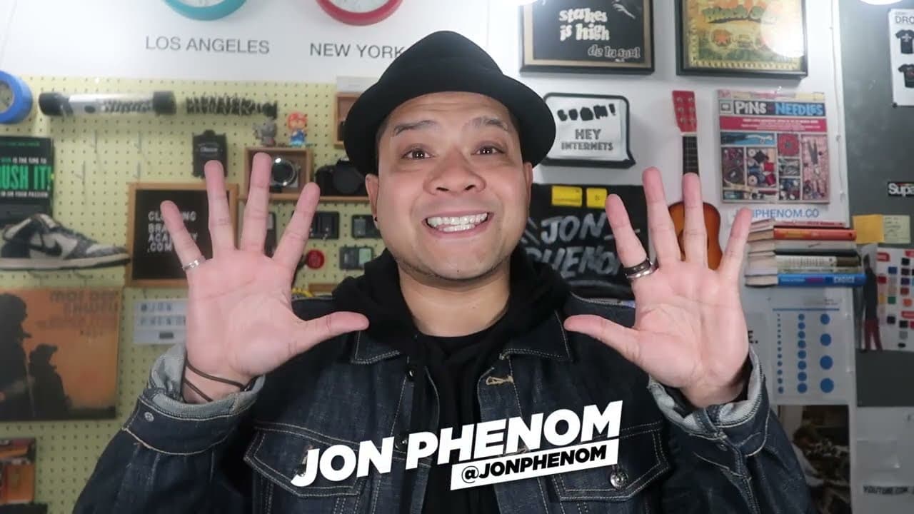 Jon Phenom smiling at camera with hands raised in creative studio space