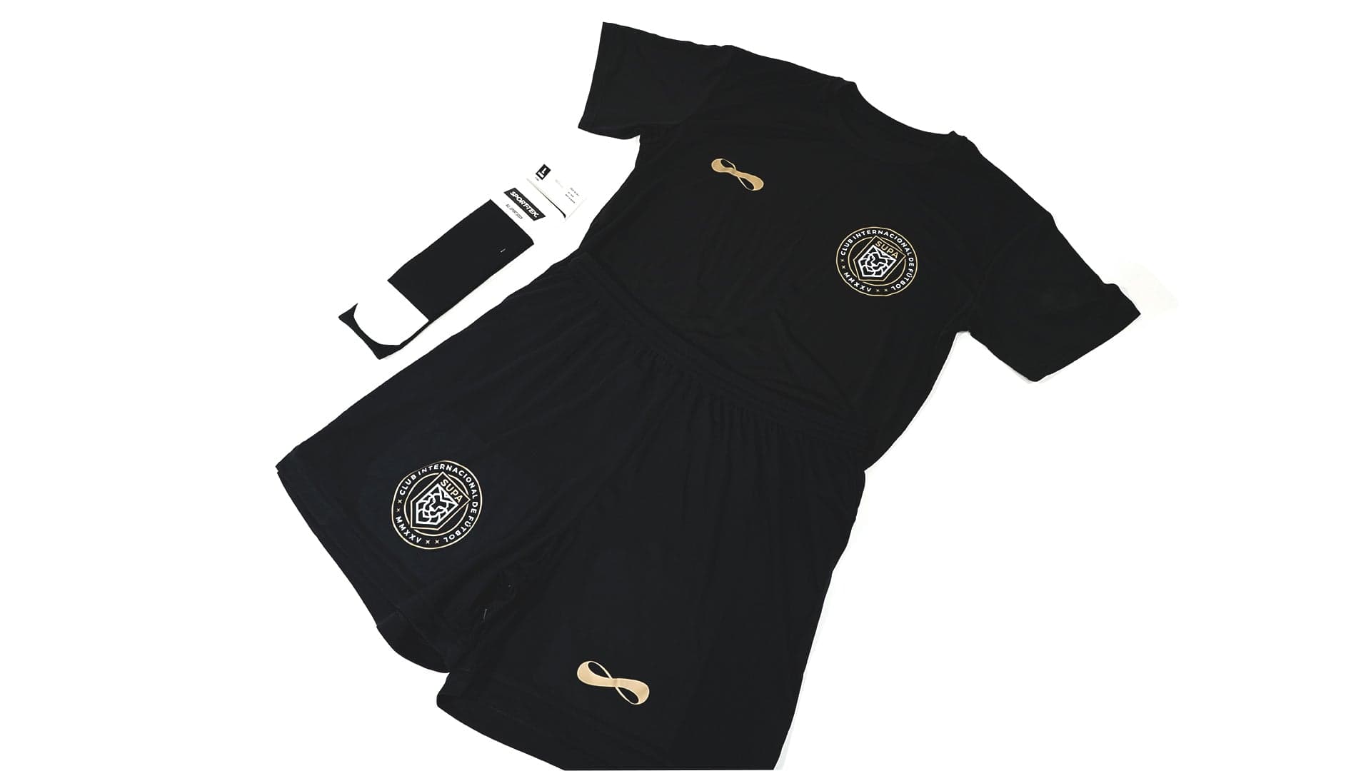 Black sports training kit with circular seal badges and gold infinity logo details, displayed with hang tag