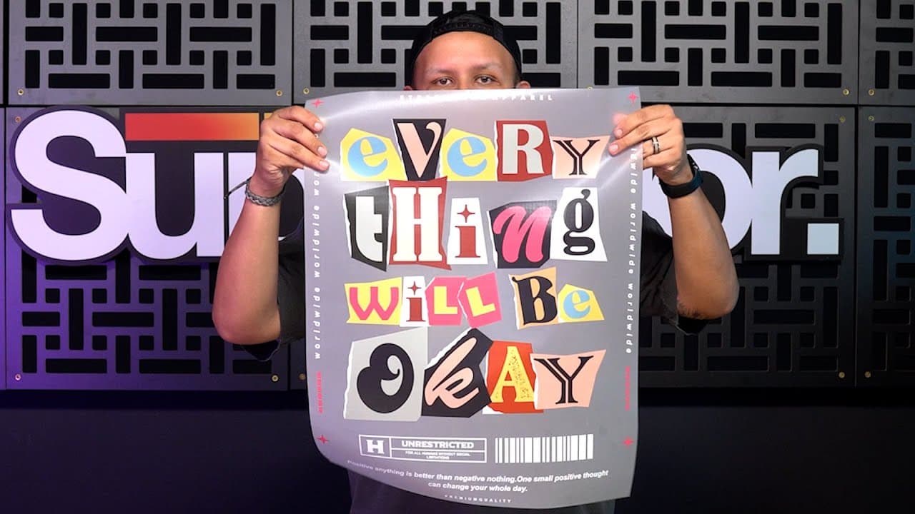 Person holding jumbo SupaDTF sheet with colorful text design against backdrop
