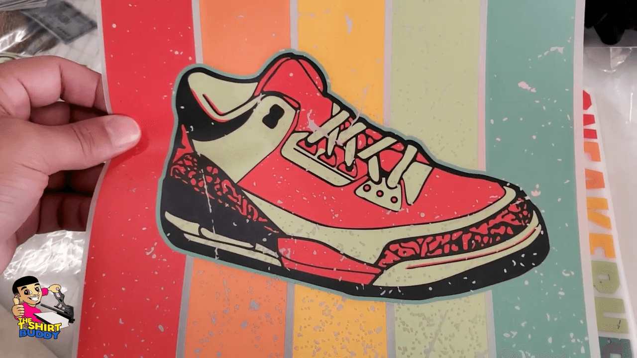 Hand holding Supacolor printed sneaker sticker on colorful striped background