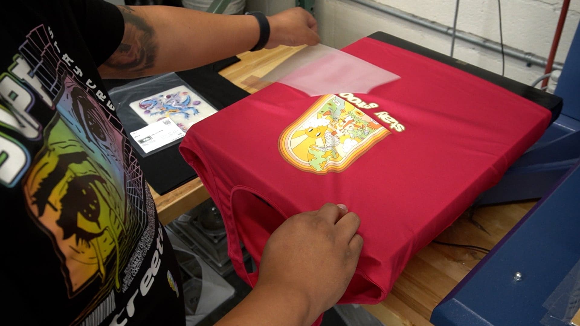 Person demonstrating heat press application on red t-shirt with Pokemon graphic design