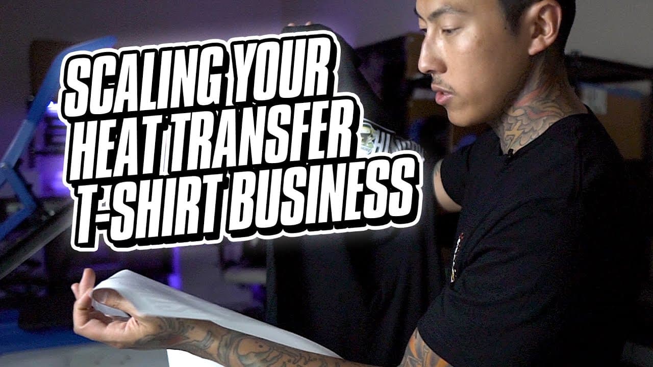 Man examining heat transfer sample during t-shirt business scaling demonstration